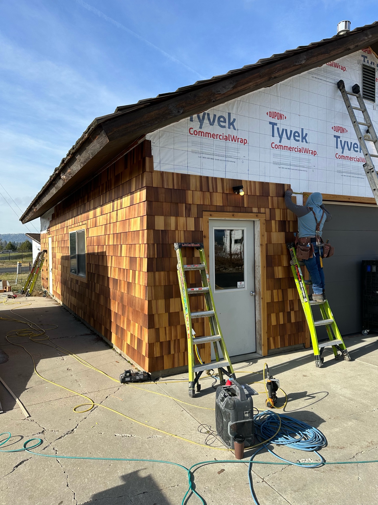 During photo of McCall Smoke Jumper Base outbuilding — new cedar shake siding being installed on lower half with Tyvek CommercialWrap above